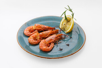 Seafood platter - three large shrimps on a plate, as long as a lemon. Healthy food, diet. Isolated