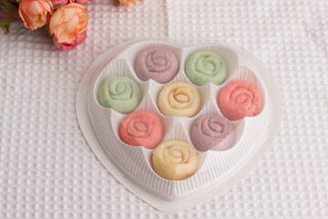 Flower shape colourful cookies in heart shape gift box on white cloth.