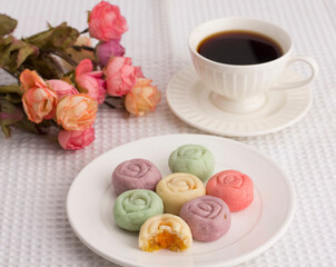 Flower shape colorful cookies served with a cup of coffee on white cloth.