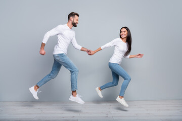 Full size profile photo of nice millennial brunet couple run wear white shirt jeans footwear isolated on grey background