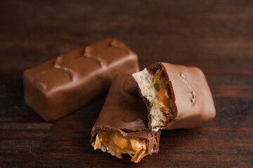 Chocolate bars with caramel, nuts and nougat on wooden table, closeup