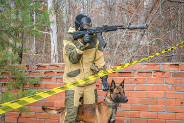 A soldier armed with a submachine gun in a gas mask with a service dog in a dangerous combat zone....