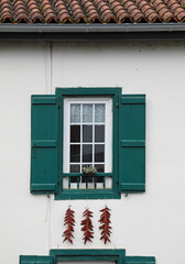 Fototapeta na wymiar espelette pimientos rojos colgados el la fachada de una casa con ventanas verdes francia país vasco francés 4M0A8329-as21