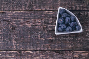 Blueberries in a bowl on the texture of an old tree.  Close-up, flat lay