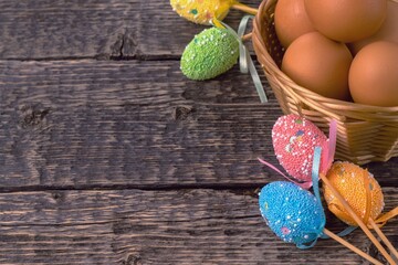 Wicker basket with eggs and decorative bright Easter decorations on the background of the texture of the old wood. Easter holiday concept