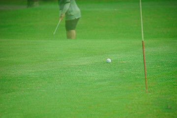 golfer putting green ball into hole