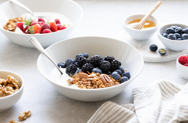 Granola with yogurt, blueberries and blackberries on a concrete background
