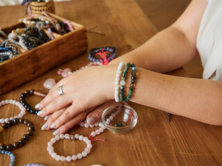 Several bracelets made of natural stones on the hands of a craftswoman. Handmade concept