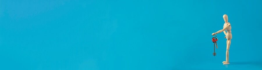 Banner with little wooden man holds the keys to the house.  Investing in real estate and buying a house. Real estate and mortgages.  Concept for buying and renting house.