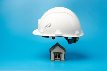 Fototapeta na wymiar House insurance concept. Insured house under protection of helmet.