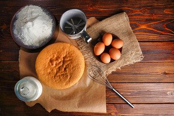 Flat lay homemade perfect sponge cake on a wooden table, flour and eggs ingredients for cooking