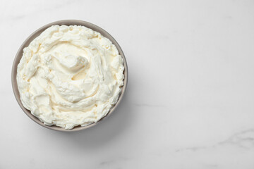Bowl of tasty cream cheese on white table, top view. Space for text
