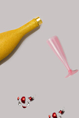 A pink cocktail glass and a gold champagne bottle on a very peri purple minimal background and red broken Christmas bauble. Party over drinking problem. Social drinking. Responsibility and control.