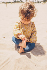 Little girl playing with sand at the beach