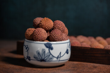 Dried litchi in a bowl on a dark yellow table;