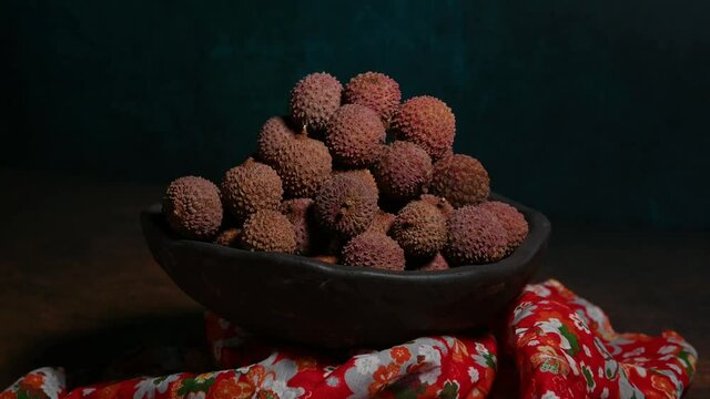 On the dark yellow textured table, the dried litchi on the plate is turning