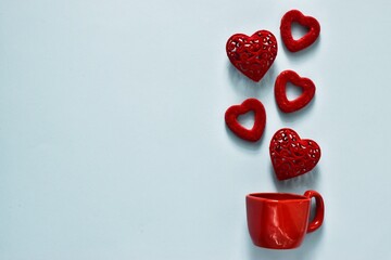 Mug and red hearts on light blue background. Flat lay composition with copy space. Romantic, St Valentines Day concept. Creative composition