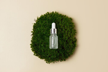 white cosmetic jar made of glass on a beige background with a pipette with water drops. Forest...