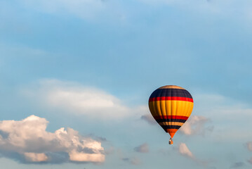 a brightly colored balloon in the blue sky against a background of white clouds