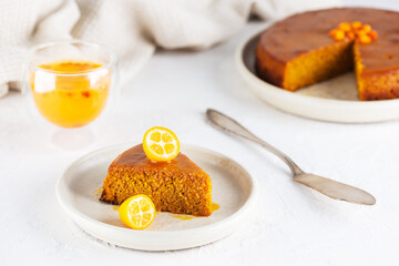 Homemade sea buckthorn cake with orange and kumquat on a plate with a glass of tea. Sugar, gluten and lactose free and vegan.