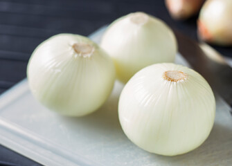 An image selected close-up focus heap onion white peeled spice taste food ingredient placed on the chopping board for eating.