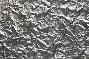 Textured background made of crumpled aluminum foil sheet. Top view.