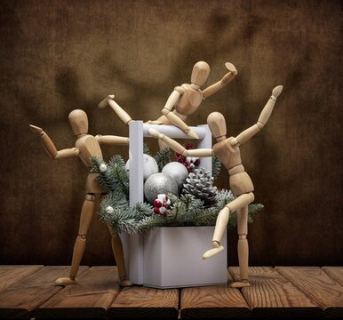Wooden men gestalta celebrate New Year and Christmas with a merry company with a Christmas tree, toys, on a wooden table and an artistic background.