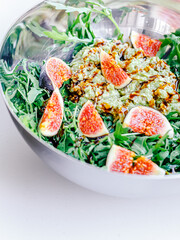 Fig salad with soft cheese and blueberries, avocado, arugula, balsamic sauce in steel bowl. Food closeup. Healthy vegetarian salad.