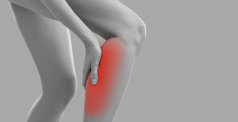 Woman touches her calf as she has sudden leg cramp. Young lady feels pain in torn or overstretched...