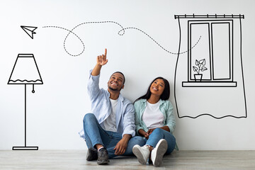 African american guy and his girlfriend imagining their new furnished home against white wall with...