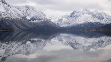 Fototapeta na wymiar The peaks and glacier valleys of the Lyngen Alps reflected in the calm fjord waters - norther Norway