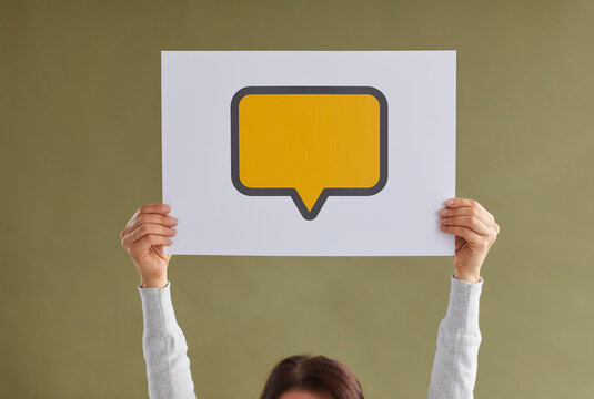 Anonymous young girl showing one yellow rectangle mockup copyspace cardboard speech bubble or reply message icon on green background. Female hand holding paper with free, blank, clean space for text