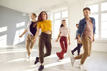 Door stickers Dance School Happy young people dance in causal clothes in studio prepare for concert. Smiling energetic millennial diverse dancers training performing together at class or lesson. Hobby and entertainment.