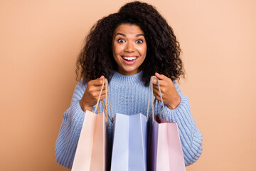 Photo of young cheerful girl hold shopping bags store gift present isolated over beige color...