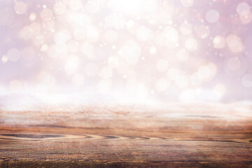 empty wooden surface covered in snow on pink background with bokeh
