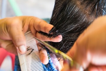 Fototapeta premium Bangkok, Thailand - November, 14, 2021 : Close-up of the hairdresser cutting female hair cutting scissors at Bangkok, Thailand.