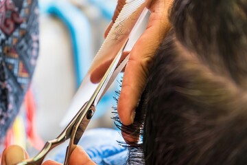 Obraz na płótnie Canvas Bangkok, Thailand - November, 14, 2021 : Close-up of the hairdresser cutting female hair cutting scissors at Bangkok, Thailand.