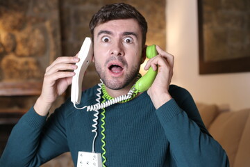 Messy man using two landline telephones at the same time