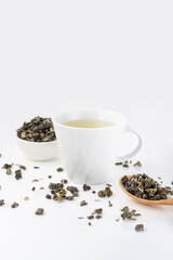 Fototapeta na wymiar White mug with green tea on a white background. Tea leaves and a wooden spoon.