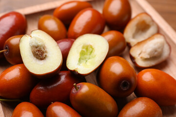 Fresh Ziziphus jujuba fruits on wooden plate, closeup