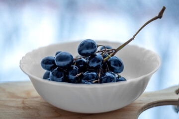 brush of black shiny grapes in white dishes, contrast of black and white