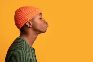 Profile Portrait Of Young Black Guy In Orange Hat Sending Air Kiss