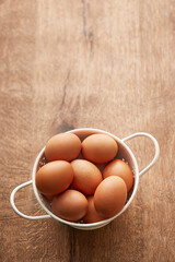 Eggs in a bowl. Brown eggs on a wooden background viewed from above. Top view. Copy space
