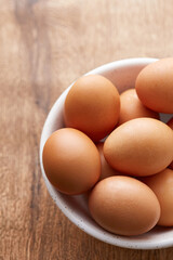 Eggs in a bowl. Brown eggs on a wooden background viewed from above. Top view