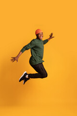 Fototapeta na wymiar Portrait Of Cheerful Black Young Guy Jumping In Air Over Yellow Background