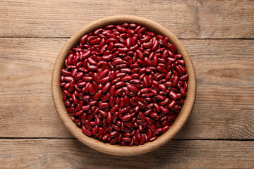 Raw red kidney beans in bowl on wooden table, top view