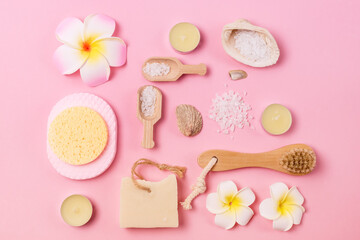 Sea Salt Aroma Candles Face Sponges and Bamboo Face Brush Plumeria Flower Natural Soap Pink Background SPA Frame Top View Horizontal Wellness