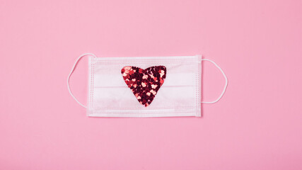 White medical mask with sparkles red confetti on a pink background St Valentine and COVID 19...