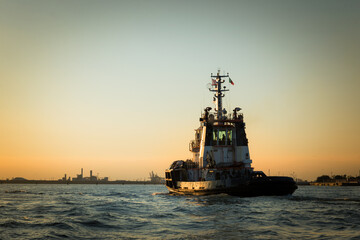 Tugboat at venice at sunset in front of industriel site of Marghera