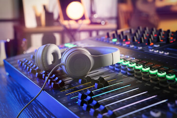 Professional mixing console with headphones on table in radio studio, closeup